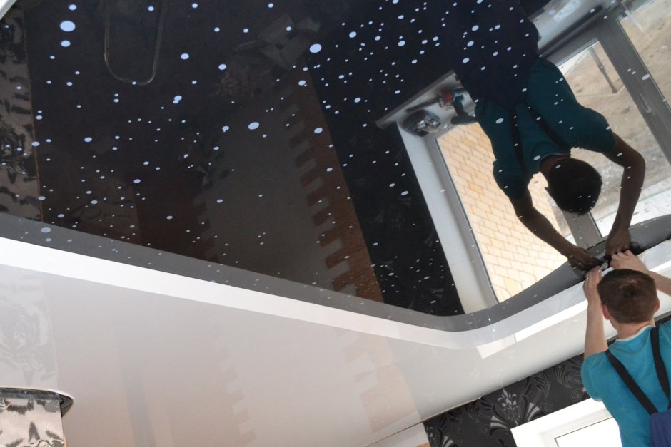 Натягивают натяжной потолок мастера